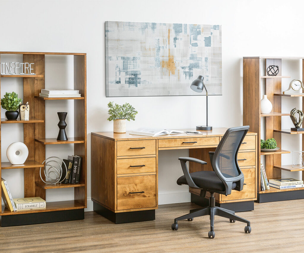Home office with a wood desk, open bookcases and an upholstered chair